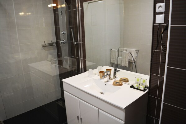 Une salle de bain moderne avec un lavabo blanc, une douche en verre et un grand miroir.