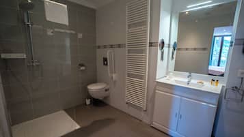 A modern bathroom with a shower, toilet, and a vanity with a mirror.
