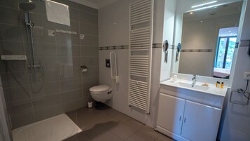 Un baño moderno con ducha, inodoro y tocador con espejo.