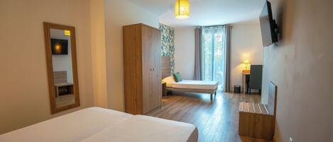 Une chambre d’hôtel équipée d’un lit, d’un bureau, d’une chaise, d’une télévision et d’une fenêtre avec des rideaux.