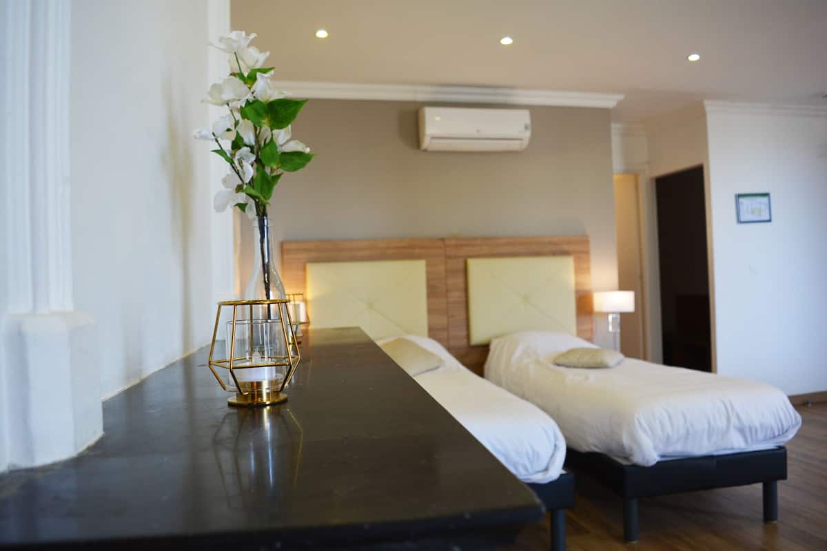 A hotel room with a bed, bedside table, and a vase with flowers.