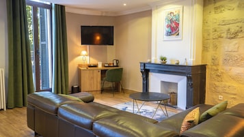 Una sala de estar con un sofá, una chimenea, un televisor y un escritorio con una silla.