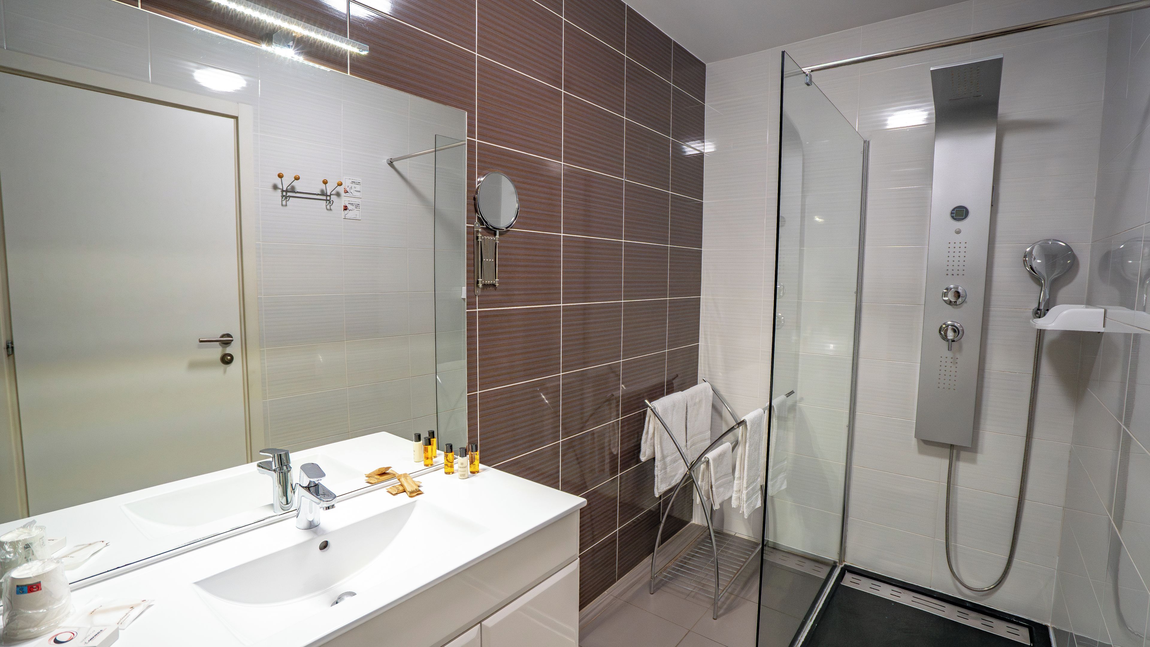 Een moderne badkamer met een wit wastafelmeubel, spiegel en douche.