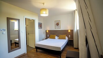 Un dormitorio con cama, lámparas de noche, un espejo y una puerta.