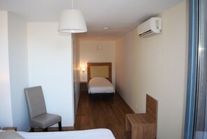 Une chambre d’hôtel équipée d’un lit, d’une chaise, d’une table de chevet, d’une lampe et d’un appareil de climatisation.