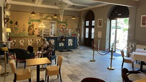 Ein Restaurant mit Wandmalerei, Kronleuchtern und Blick auf die Straße.