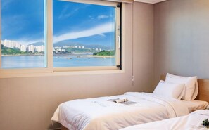 A hotel room with a large window offering a view of a cityscape and water. - Sea Star Hostel Yeosu (Yeosu)