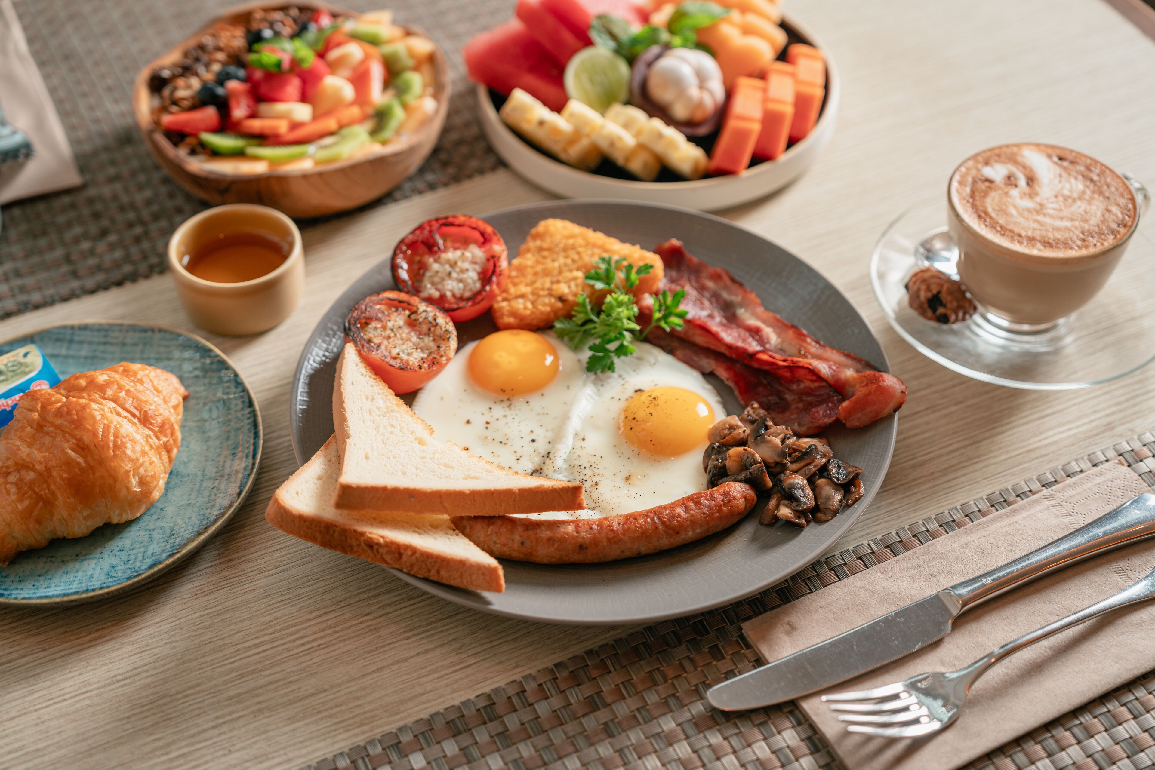 A breakfast setting with toast, eggs, bacon, and a cup of coffee on a table.