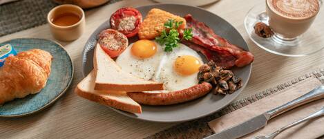 Un desayuno con tostadas, huevos, tocino y una taza de café sobre una mesa.