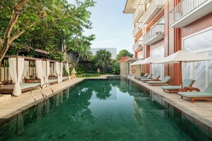 A swimming pool with lounge chairs and a covered seating area.