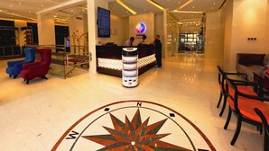 Vestíbulo de hotel con mostrador de recepción, zona de estar y un gran diseño de brújula en el suelo.