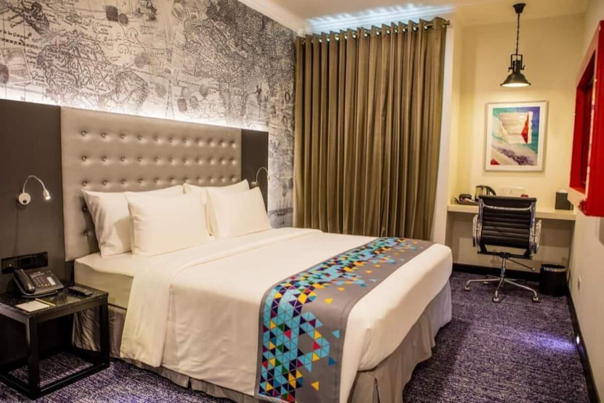 Habitación de hotel con una cama grande, un escritorio, una silla, un teléfono y un papel tapiz con mapa.