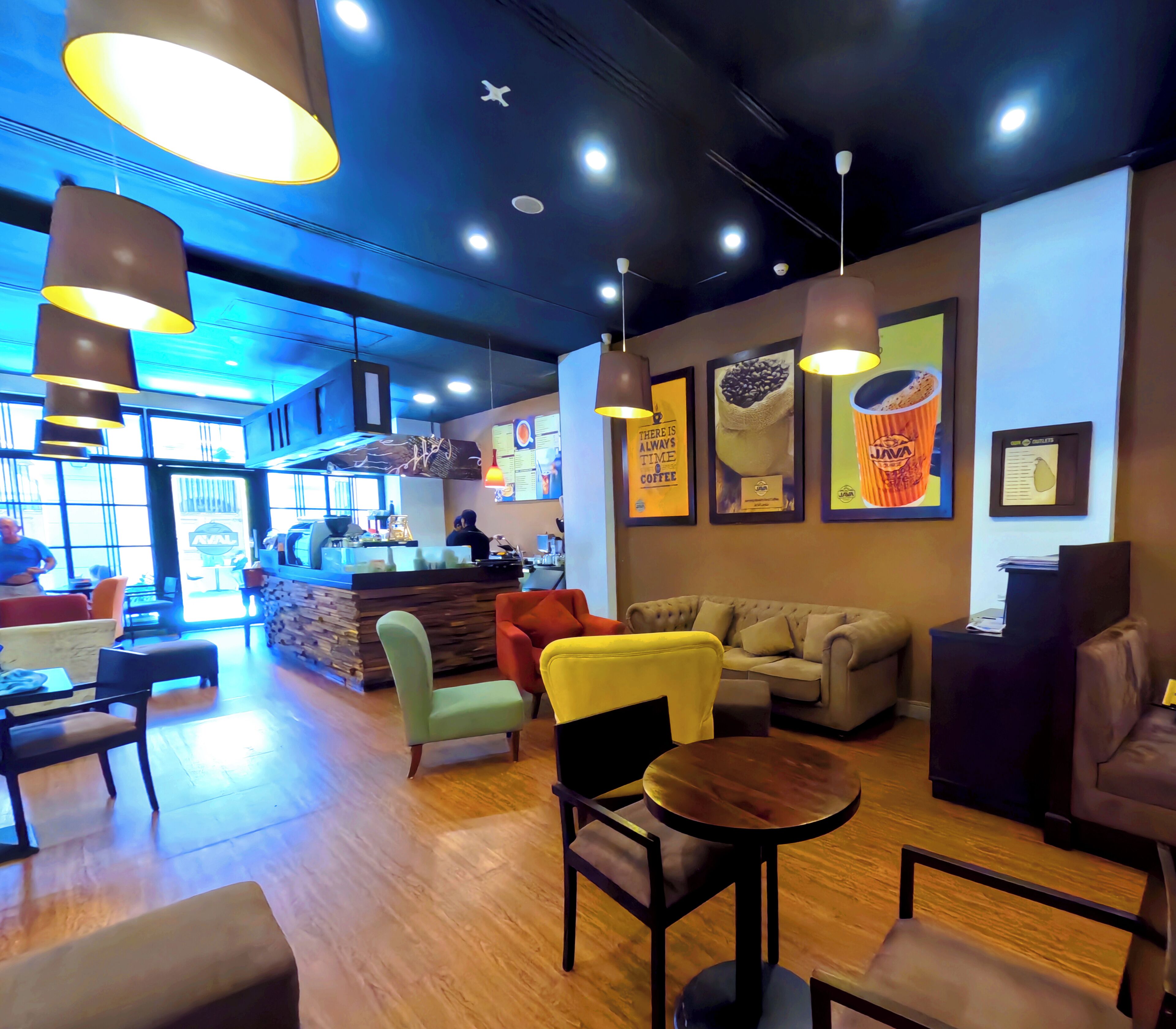 A cozy cafe with wooden flooring, comfortable seating, and modern decor.