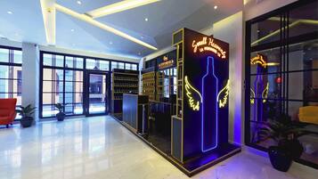 A modern hotel lobby with a glass storefront, a neon sign, and a clean, reflective floor.