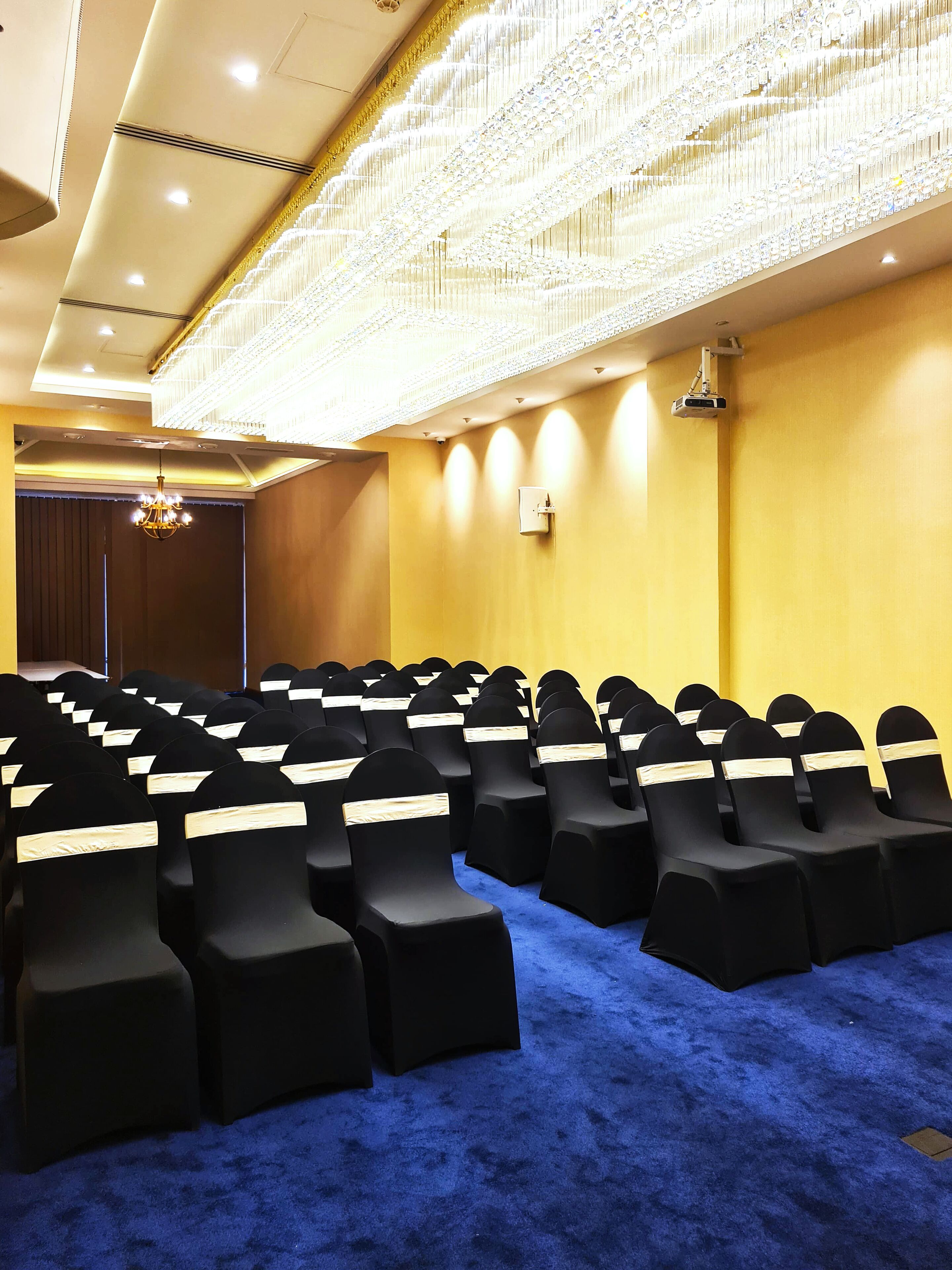Una sala de conferències amb files de cadires negres, una catifa blava i un penjoll.