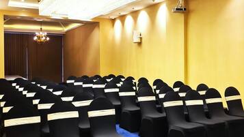 A conference room with rows of black chairs, a blue carpet, and a chandelier.