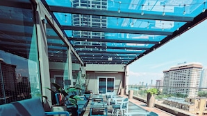 Terraza en la azotea con mobiliario exterior, plantas en macetas y vistas a la ciudad.
