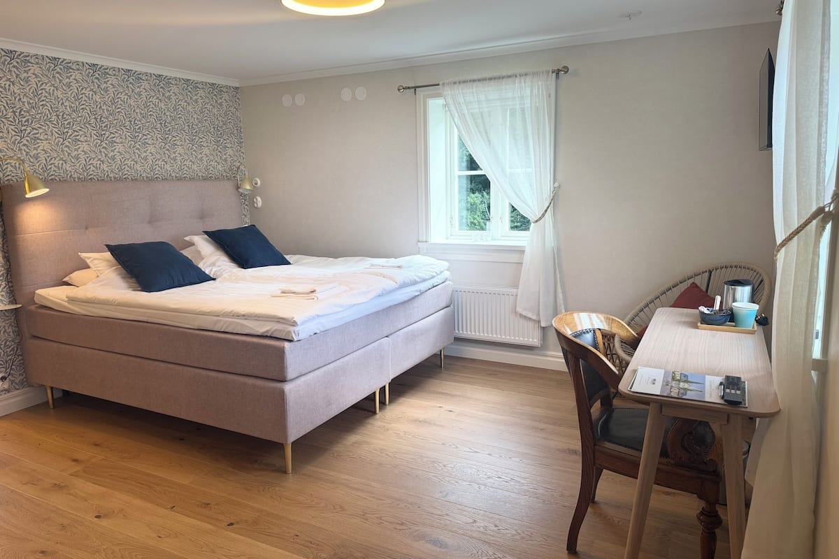 A bedroom with a bed, bedside table, chair, and window.