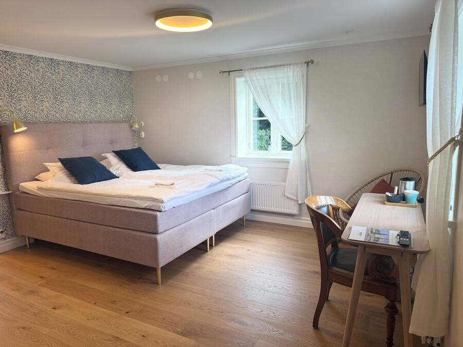 A bedroom with a bed, bedside table, chair, and window.