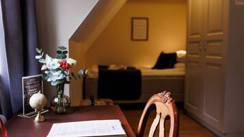 A cozy room with a wooden table, a globe, a vase with flowers, and a bed with a black pillow.