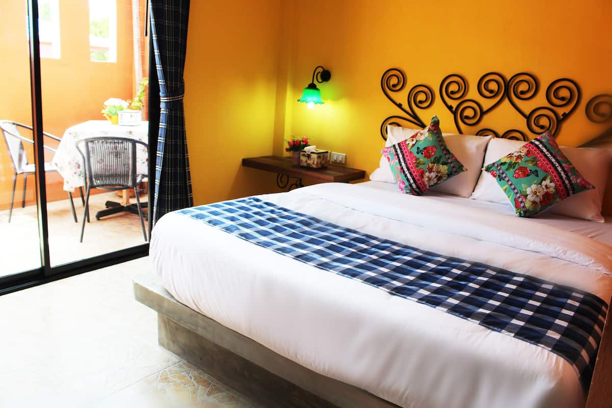 Habitación de hotel con cama, mesita de noche, lámpara, silla y vista al exterior.