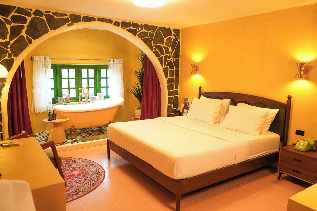 Un dormitorio con una cama grande, una bañera y un arco de piedra.