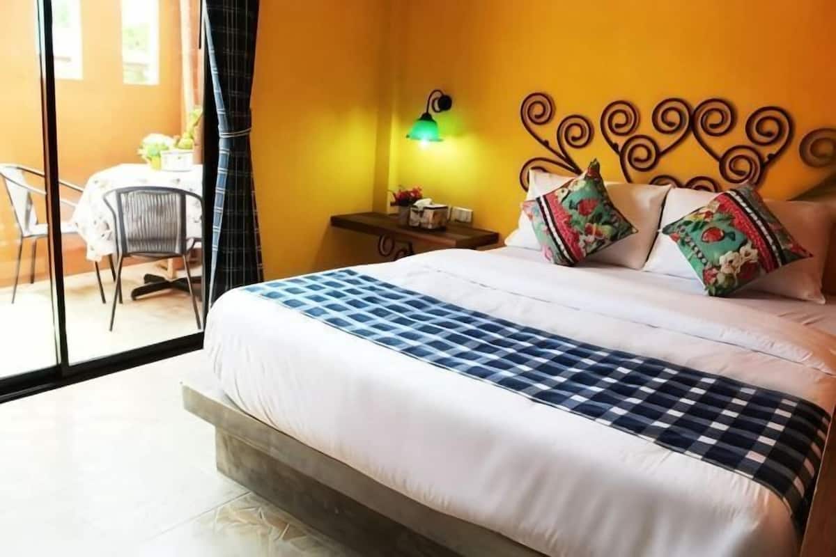 Un dormitorio con cama, mesita de noche, lámpara y una silla.