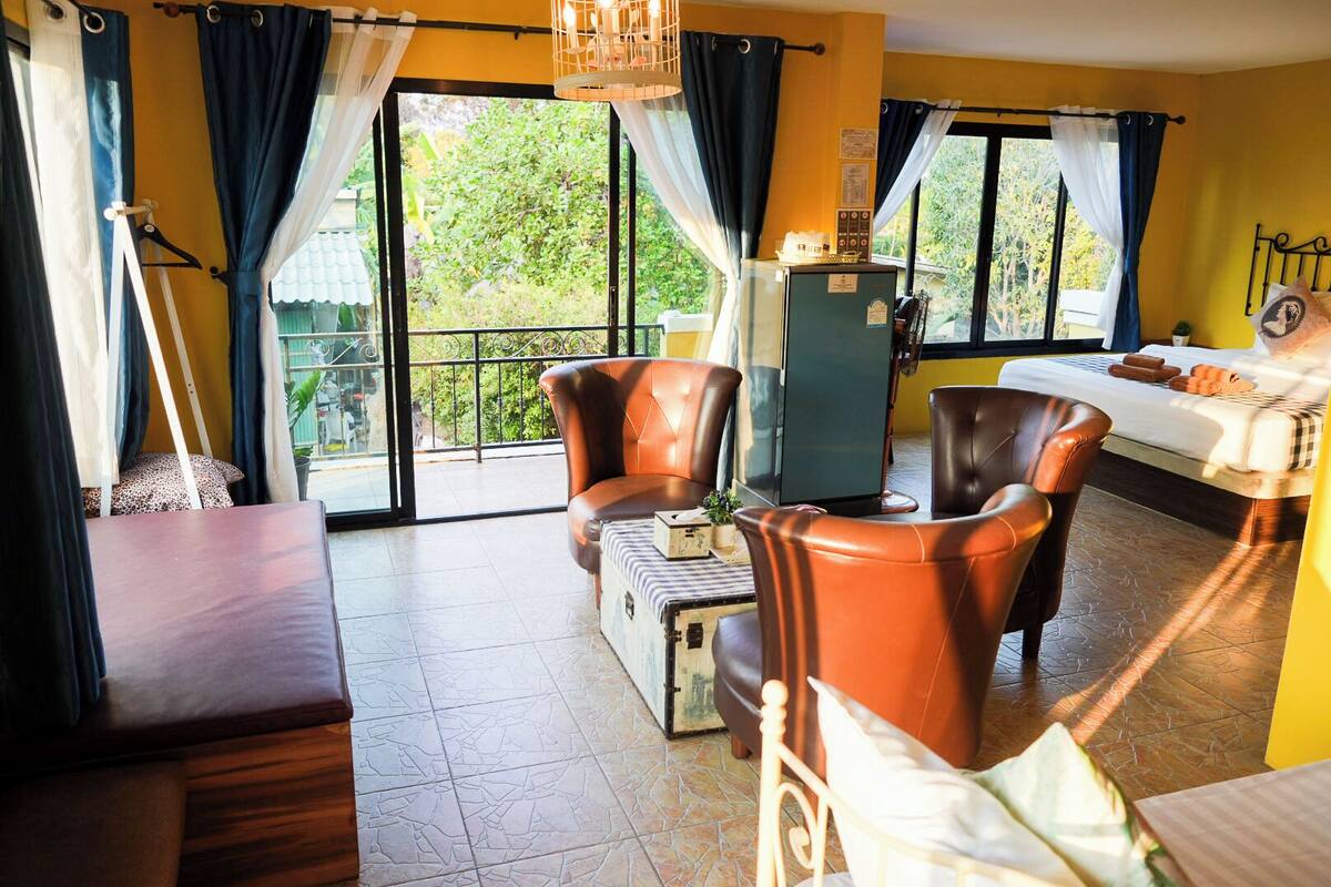 Una habitación de hotel con una cama, dos sillones de cuero, una mesita pequeña y un minibar.