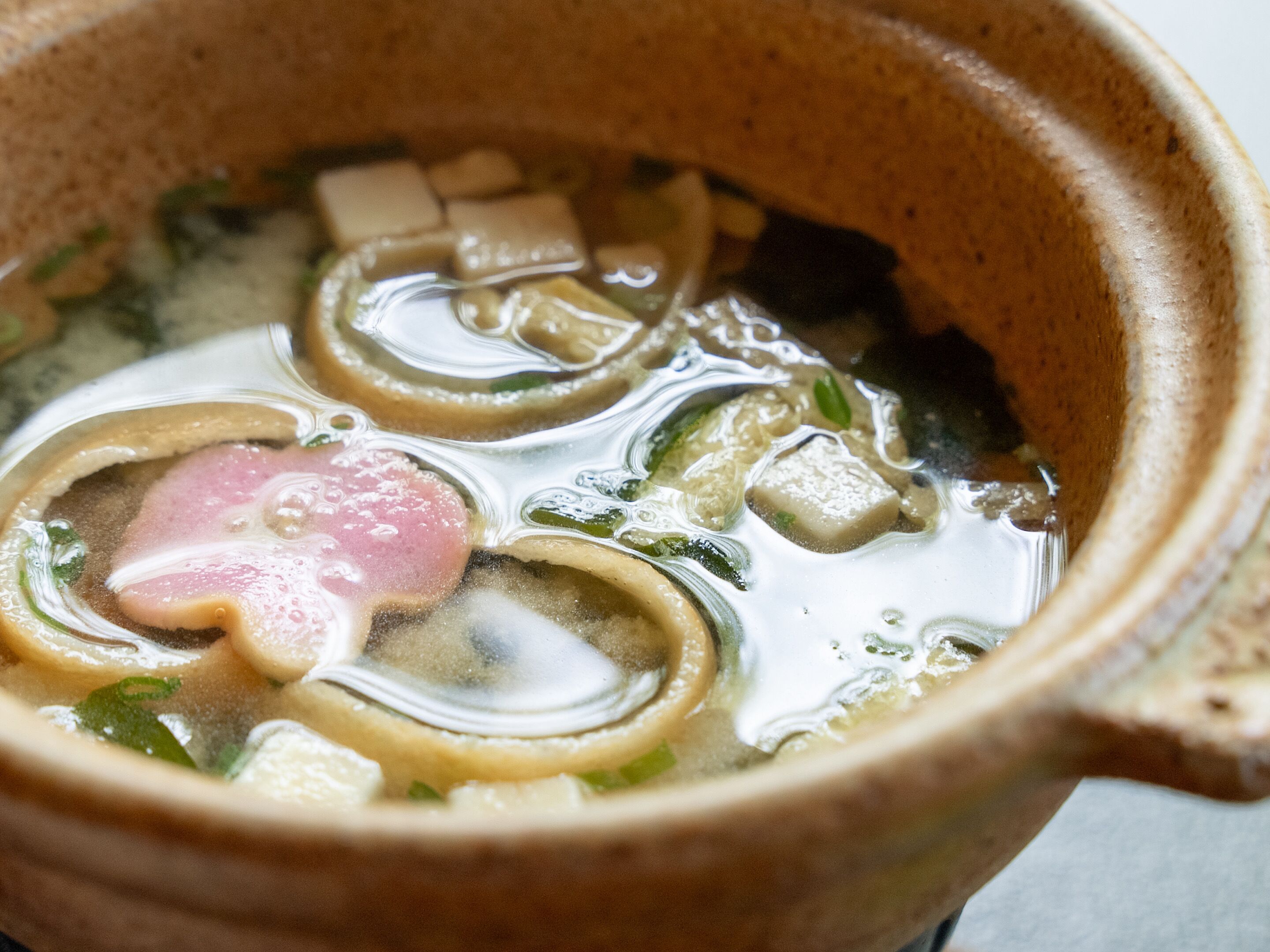 Primer plano de una olla japonesa tradicional con ingredientes variados como tofu, verduras y carne.