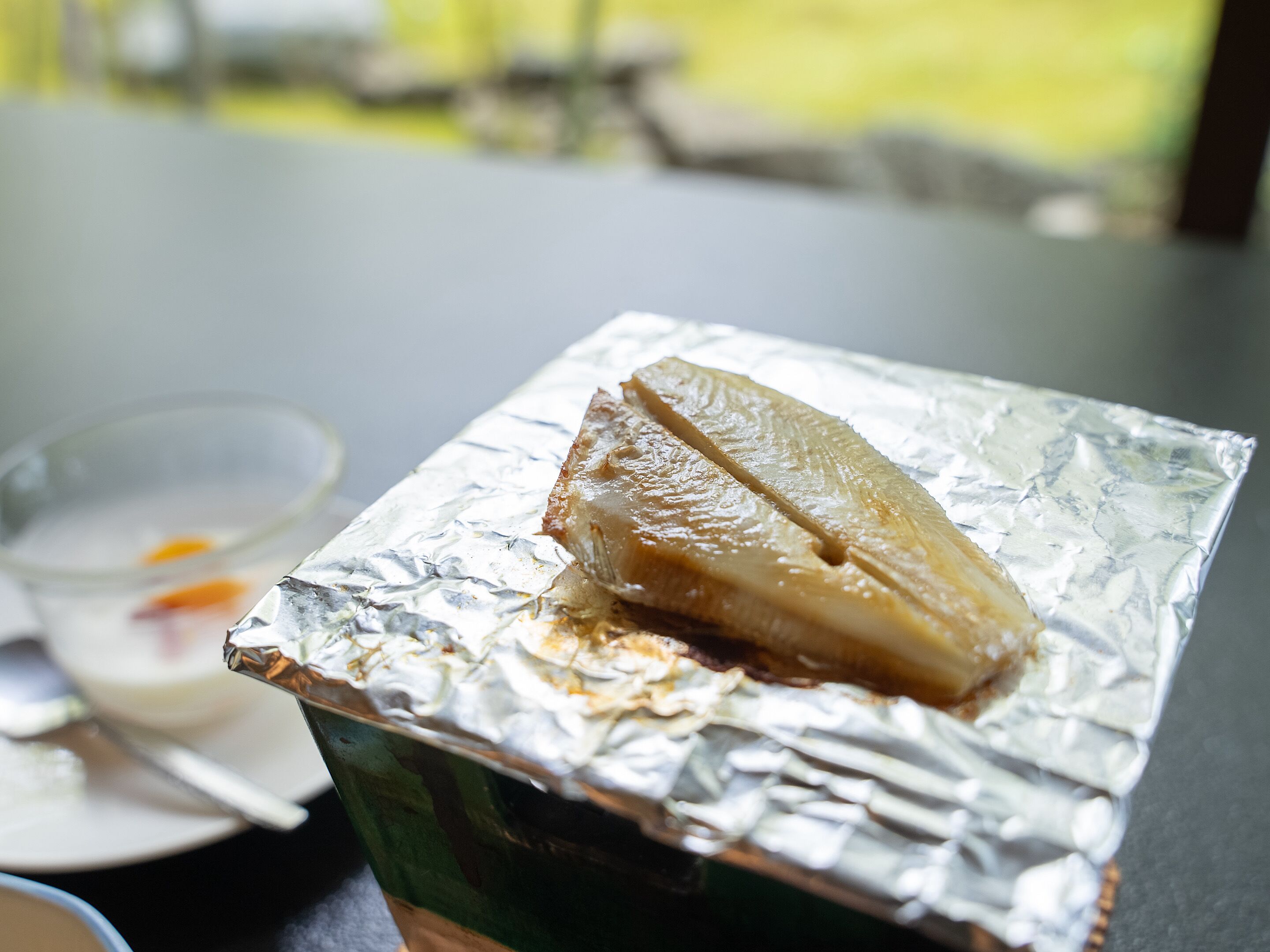 Comida sobre papel alumínio, com um recipiente verde ao lado.