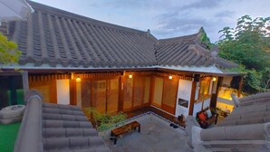 Ein traditionelles koreanisches Gebäude mit einem Ziegeldach, Holztürgittern und einem kleinen Innenhof mit einer Bank.