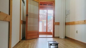 A traditional Japanese room with a sliding door, wooden flooring, and a small black table. - Gangneongjeon Hanok Stay (Jeonju)