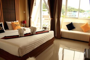 A hotel room with a large bed, a sofa, and a view of buildings through the window.