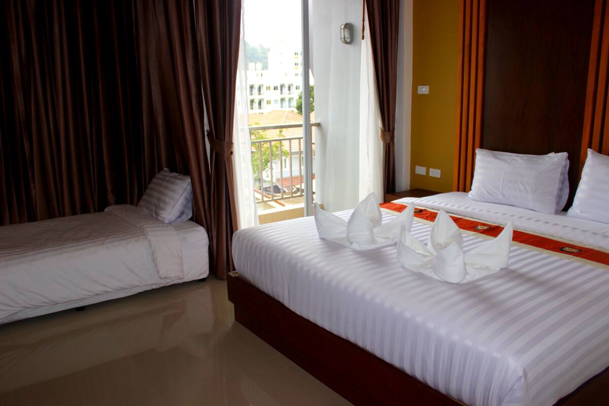 A hotel room with two beds, a balcony, and curtains.