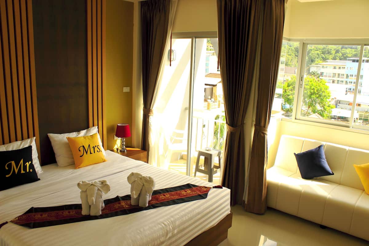 A hotel room with a large bed, a sofa, and a view of the city.