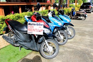 A row of motorbikes parked in a lot with a sign indicating they are for rent.
