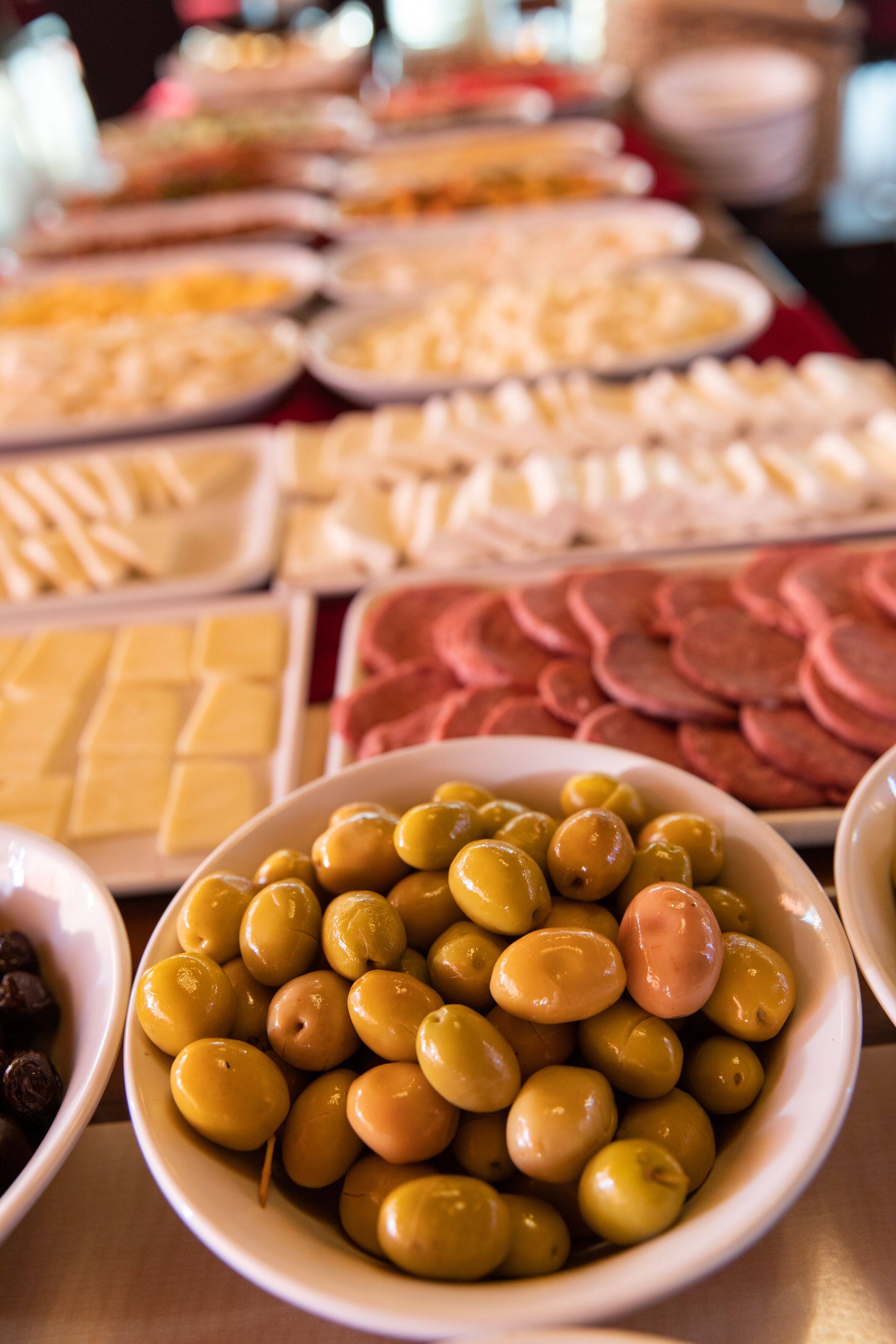 A buffet with various food items including olives, cheese, and sliced meats.