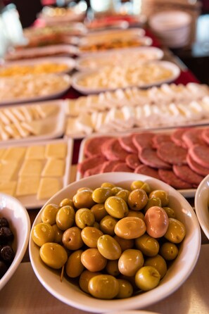 A buffet with various food items including olives, cheese, and sliced meats.
