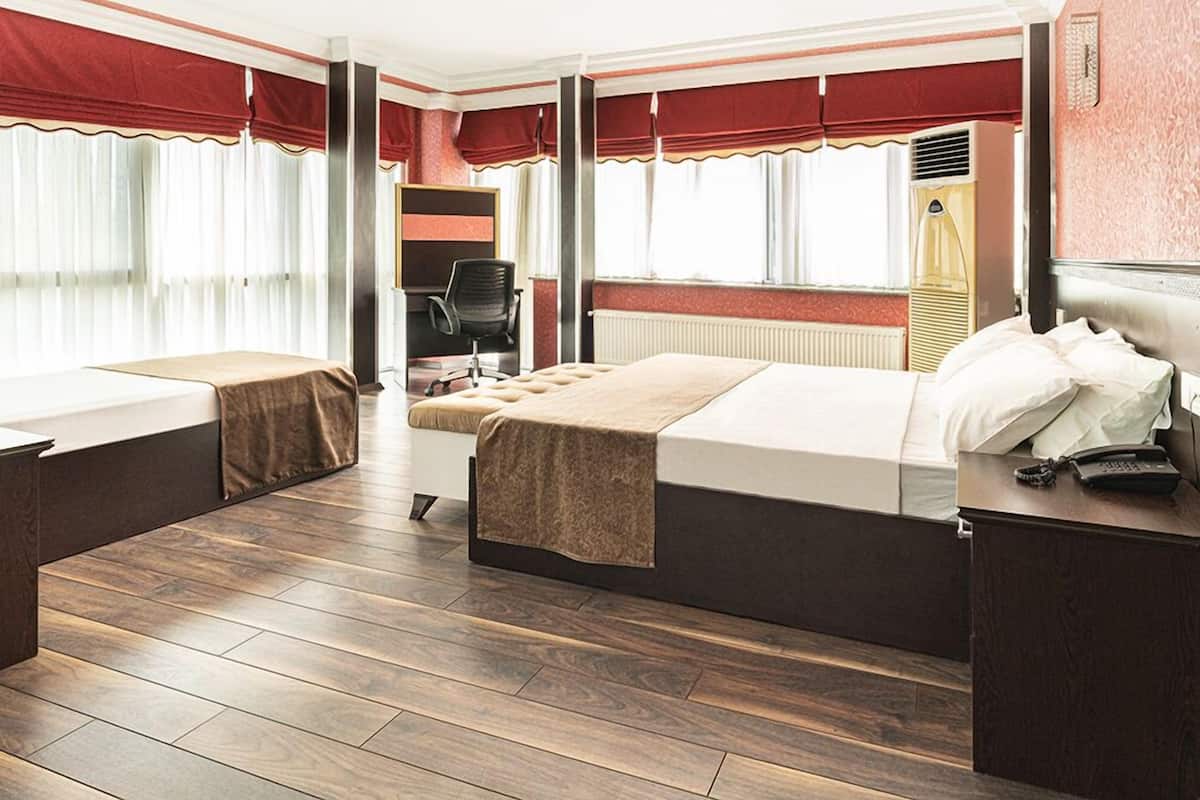Een hotelkamer met twee bedden, een bureau, een stoel en een radiator.