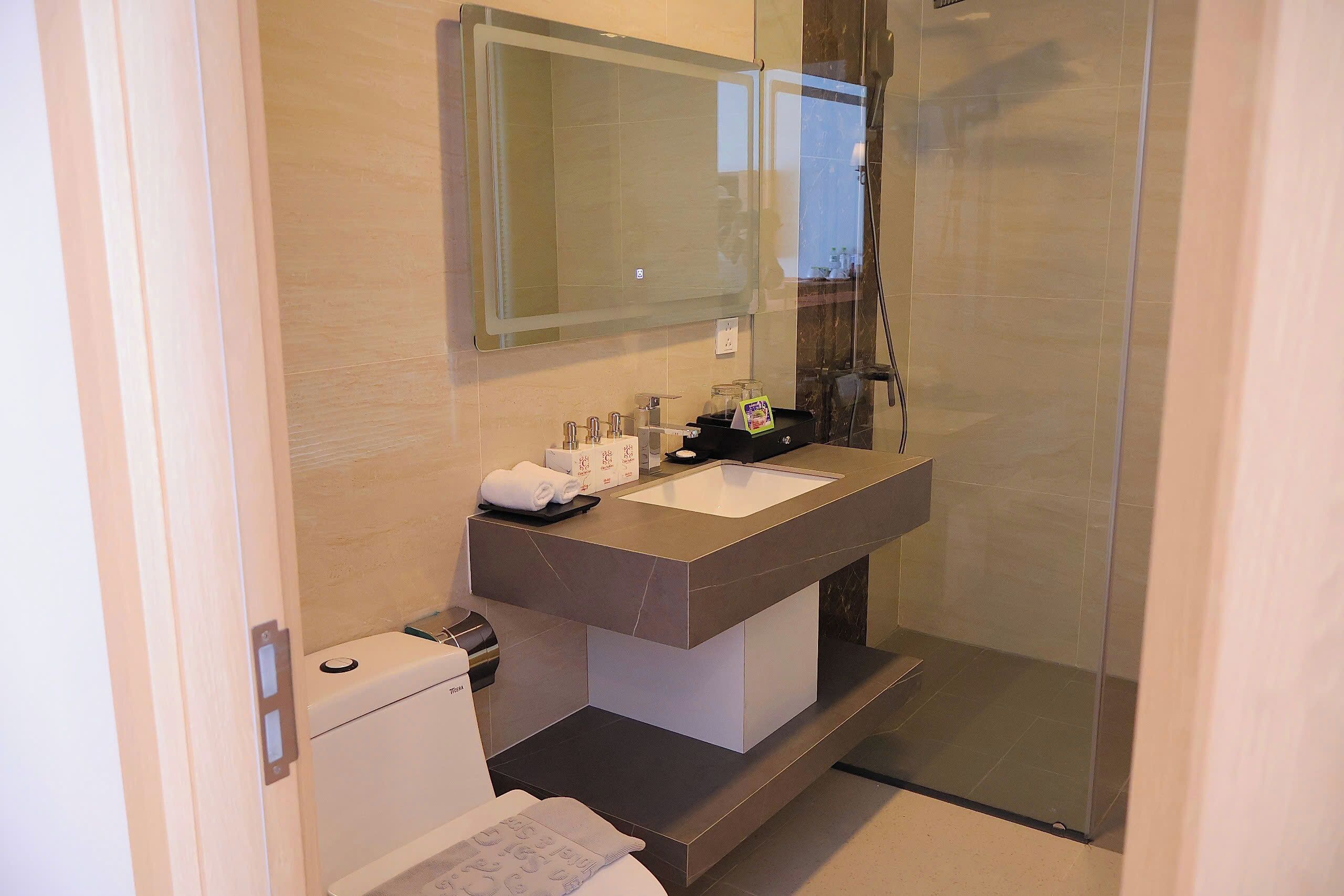 A modern bathroom with a large mirror, a white sink, and a glass shower enclosure.