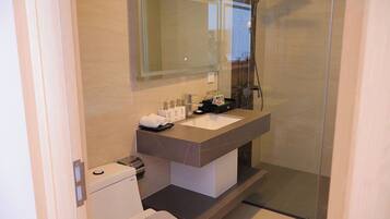 A modern bathroom with a large mirror, a white sink, and a glass shower enclosure.