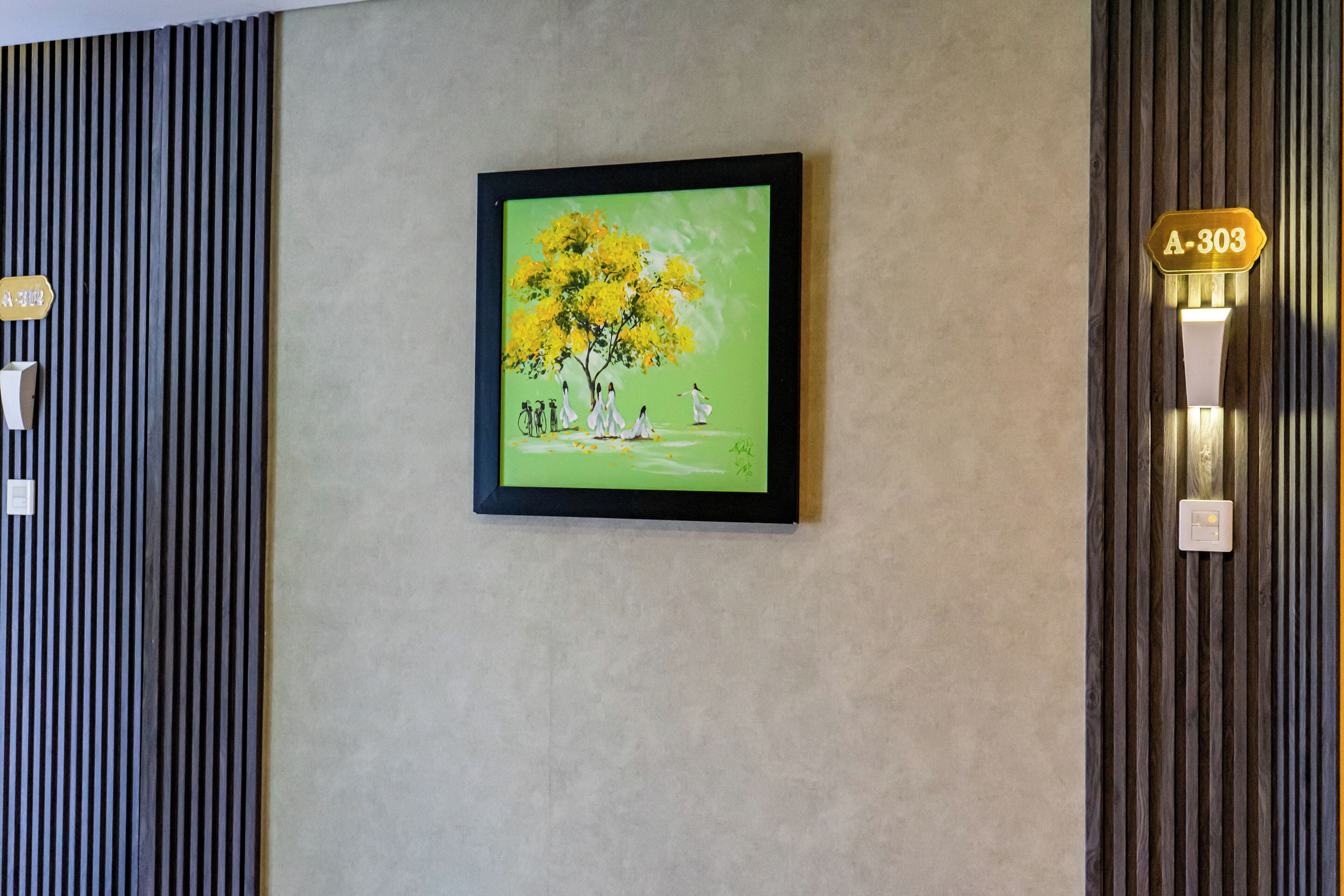 A framed painting of a tree with people on a wall.