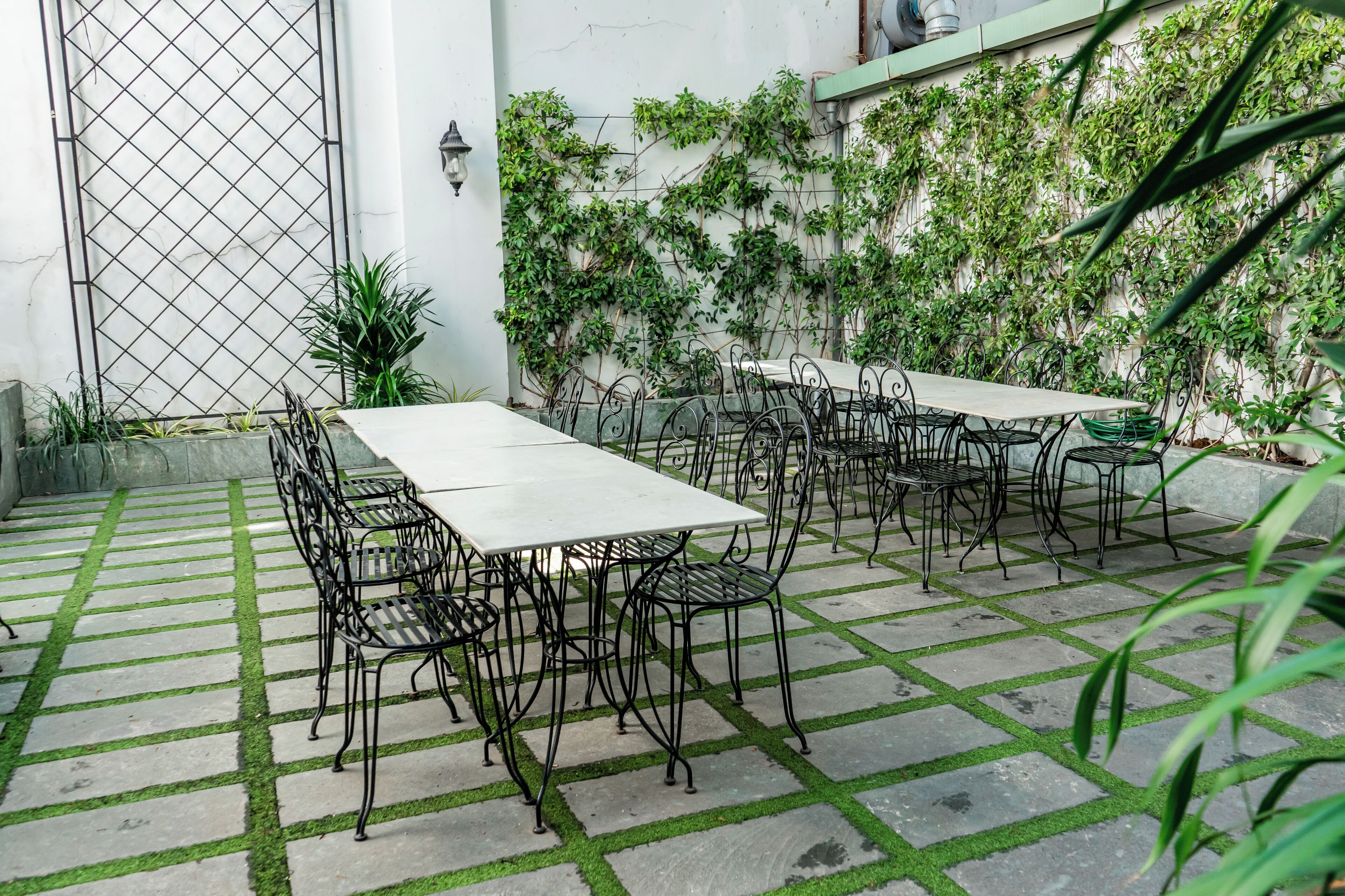 Un patio al aire libre con suelo de baldosas, sillas y mesas de metal.