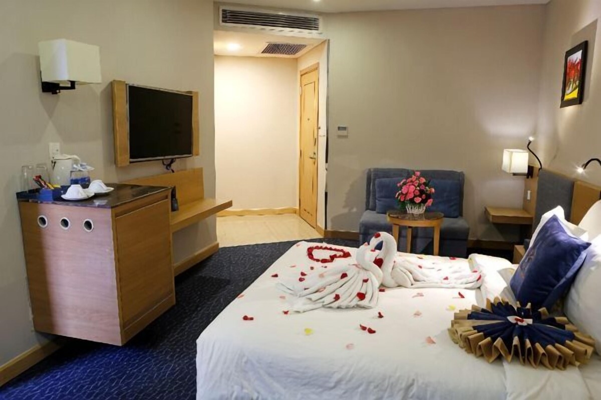 Una habitación de hotel con una cama, un escritorio, una silla, un televisor y una puerta.