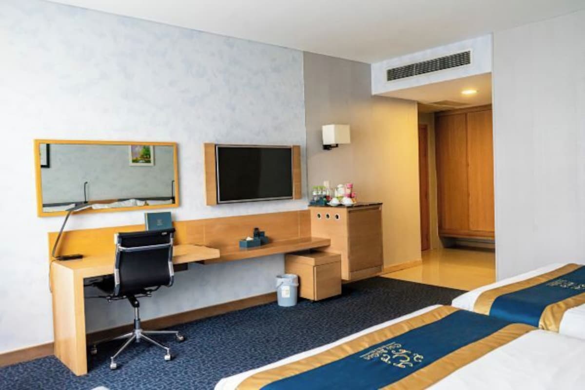Una habitación de hotel con escritorio, televisión, cama y armario.