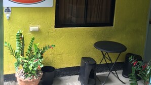 Pared amarilla con un letrero de Ellen's Resort & Aparthotel, una mesita negra pequeña y plantas en macetas.