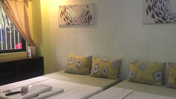 Habitación de hotel con dos camas, una ventana con cortinas y dos obras de arte colgadas en la pared.