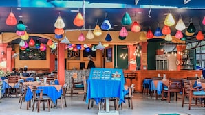 A restaurant with tables covered in blue tablecloths, hanging paper lanterns, and a sign reading "KRAC". - Sugar and Spice Inn (Karon)
