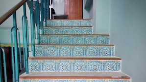 A staircase with ornate blue and white tiles and a wooden handrail. - Sugar and Spice Inn (Karon)