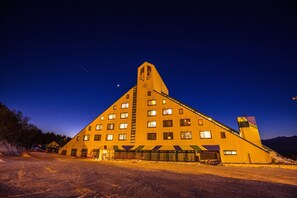 Ein großes, dreieckiges Gebäude mit zahlreichen Fenstern und einem zentralen Turm, umgeben von verschneiter Landschaft.